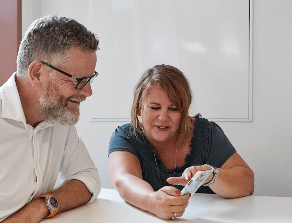Billede af to personer, der ser på en mobiltelefonskærm