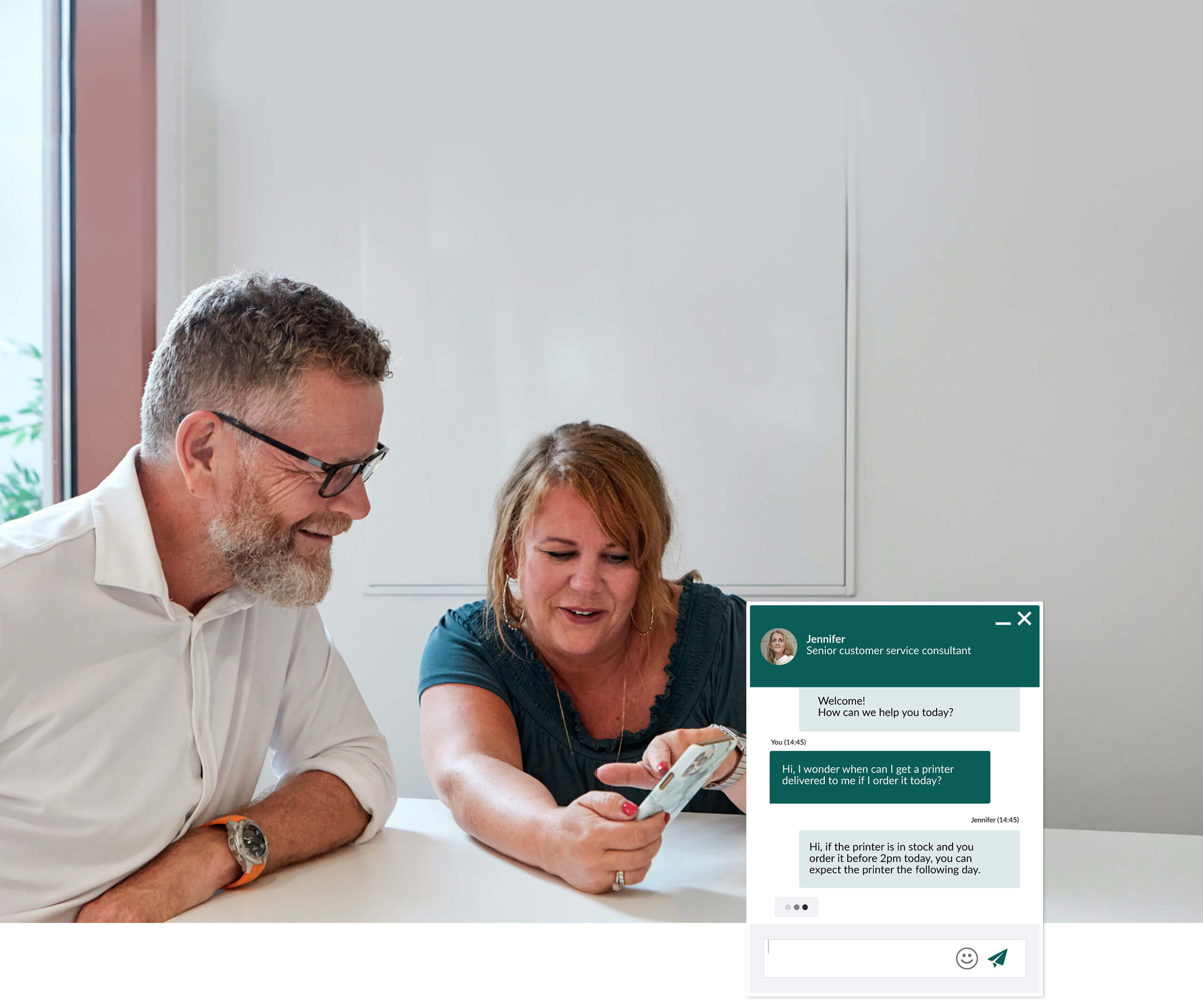 Billede af to kolleger, der ser på chat på en mobiltelefon
