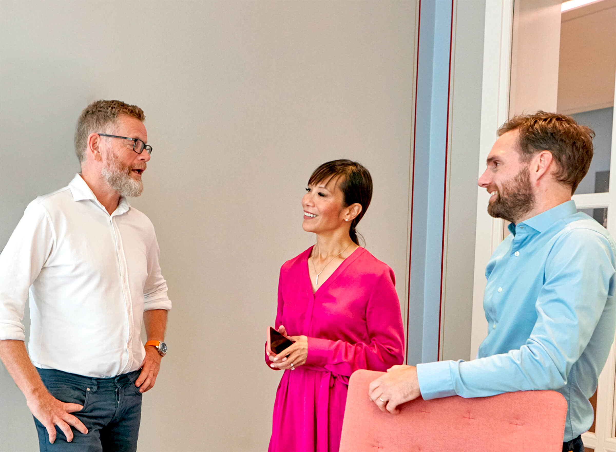 Billede af tre kolleger, der chatter på kontoret